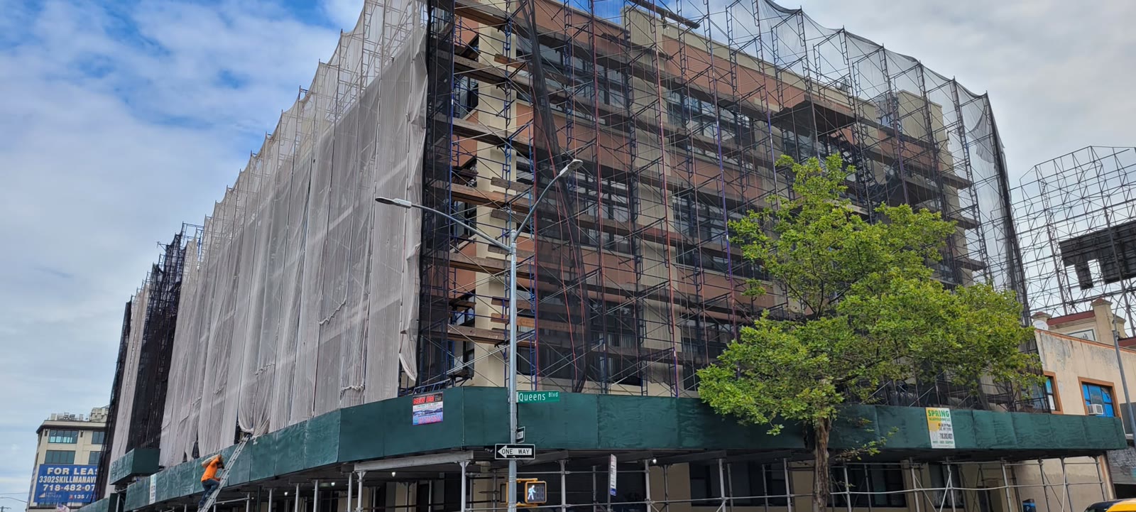 Brick apartment building wrapped in scaffolding and netting during Local Law 11 facade repairs