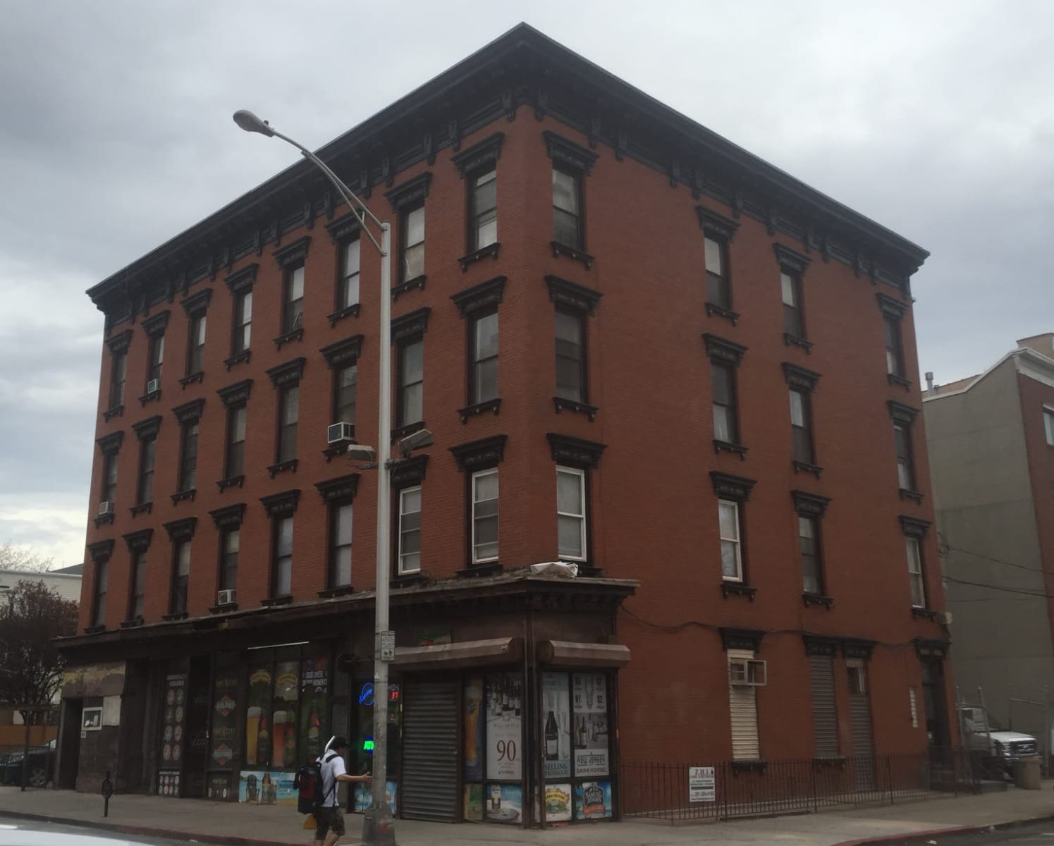 Corner brick apartment building with a parapet and cornice along the roofline