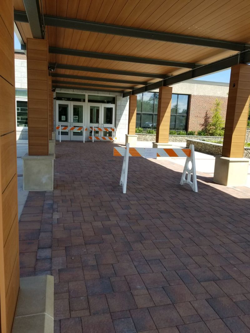 Completed herringbone brick paver plaza at the Roslyn High School entrance with cast stone plinths at the canopy columns